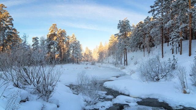 морозный солнечный день в уральском лесу с замерзшей рекой, Россия, январь