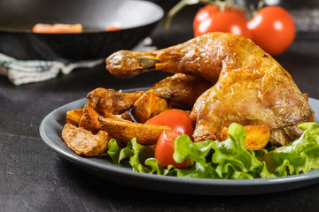 Roasted chicken legs with potato wedges and tomatoes