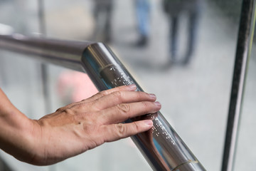 Hand reading Braille inscriptions for the blind on public amenity railing - obrazy, fototapety, plakaty