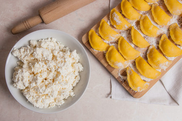 Ready for boiling vareniki, dumplings, pierogi on wooden cutting