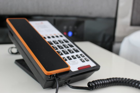 Sleek modern touchpad telephone on a bedside table in an apartment or hotel bedroom