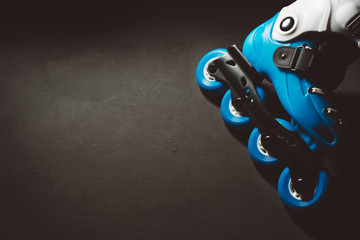 Close up view of blue roller skates inline skate or rollerblade on dark tinted grunge background