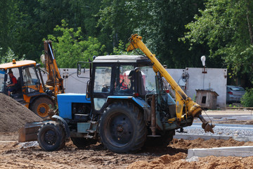 Two tractors work on construction site with gravel and sand at s