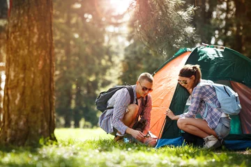 Abwaschbare Fototapete Camping Junge Camper bauen das Zelt am Wald auf.