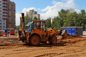 Fototapeta na wymiar Yellow tractor works on construction site at summer sunny day