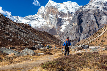 Fototapeta na wymiar Mountain Hiker walking on Footpath with high Peaks on Background