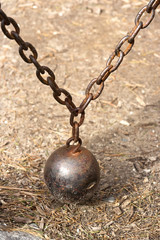 Old counterweight ball and chain still in use on gate. Vertical.