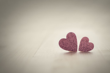 Two delicate pink hearts on vintage background toned
