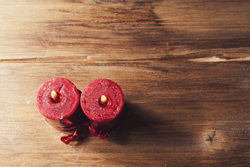 Two red candles tied with red ribbon, the symbol of Valentine's day, mimics the relationship of men and women, on wooden background from old boards