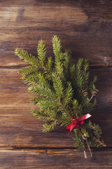 Spruce branch tied with a red ribbon, the symbol of the holiday, new year, Christmas, old vintage wooden background, on the boards