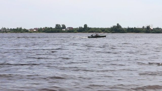 Small motor boat sails on river at sunny summer day