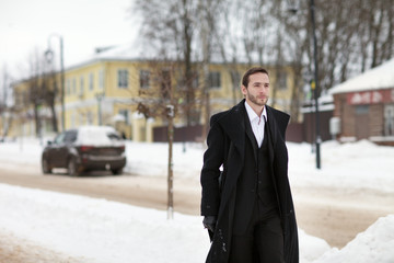 Male businessman sitting on a bench, holding a business briefcase with documents, in the winter on the street