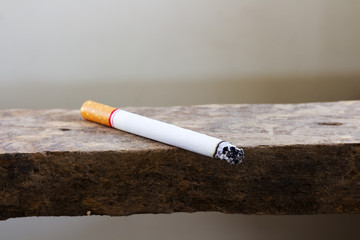 Burning cigarette with ash and smoke  on the outdoor wooden table. Bad habit concept background.
