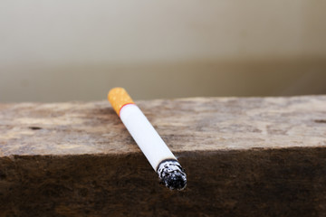 Burning cigarette with ash and smoke  on the outdoor wooden table. Bad habit concept background.