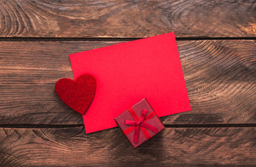 Valentines day greeting card and small gift, heart decoration over wooden background. Top view with copy space