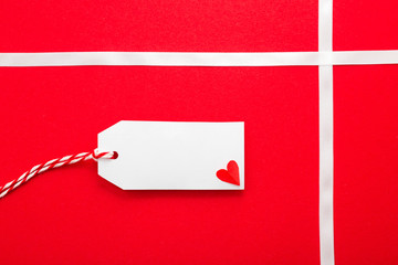 Label and small heart on red gift, place for text, Valentines Day, Christmas, New Year, Birthday.