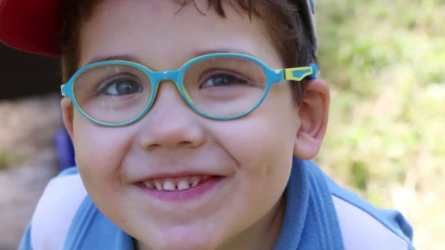 Happy cute boy in glasses and cap laughs, close up