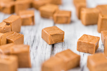 Portion of Caramel pieces on wooden background (selective focus)