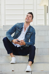 Full body handsome young man laughing with mobile phone