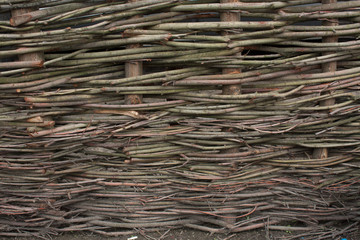 Wooden rustic fence made with chopped branches intertwined togather