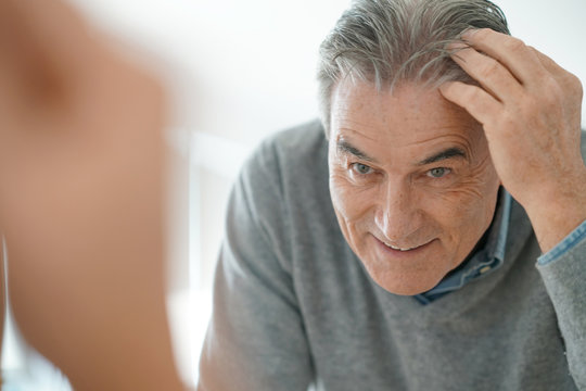 Senior Man Looking At Hair In Mirror