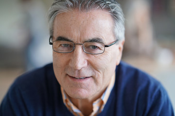 Smiling senior man with eyeglasses relaxing in armchair