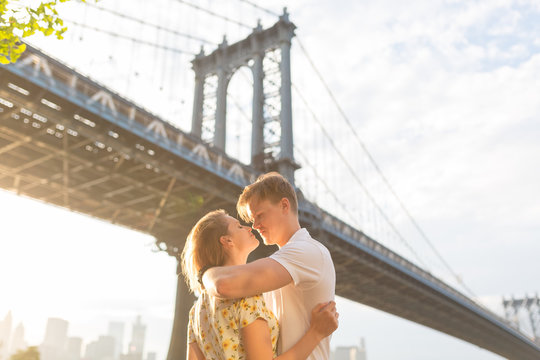 Young Beautiful Couple Hugging and Kissing Under the Brooklyn Bridge . New York City
