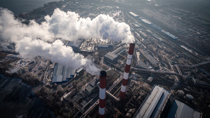 Air pollution by smoke coming out of two factory chimneys. Industrial zone in the city. Kiev, Ukraine, aerial view