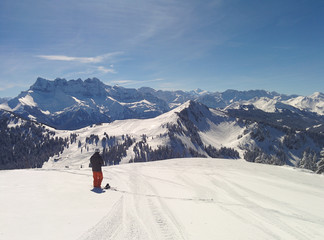 Snowboarder looking across view of Portes du Soleil ski region, The Alps, France