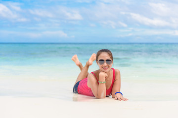 young woman and sunglasses lying on beach