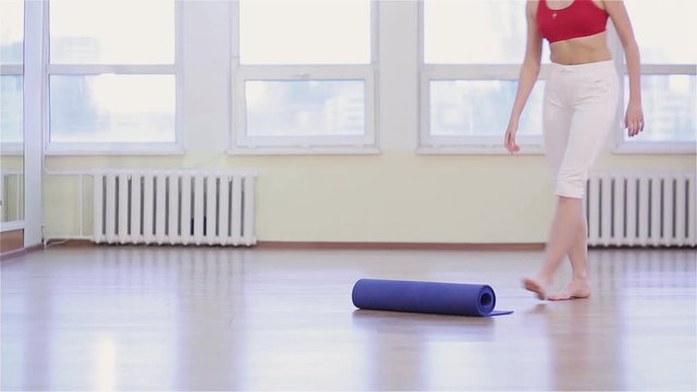 Young fit woman practicing yoga asana or pose. Young woman working out in gym, she unwraps the mat before starting yoga in gym class.