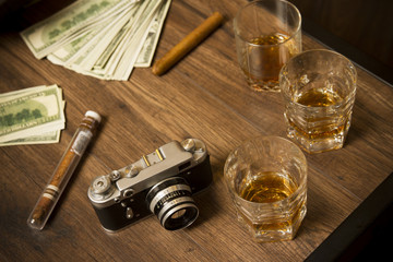 Obraz na płótnie Canvas Glass of whiskey with cigar, money and vintage camera