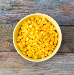 grain sweet corn in plate on old wooden table. close-up, top view
