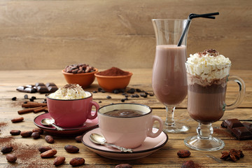 cioccolata calda e cioccolata con panna in tazza e bicchiere su tavolo coperto di cacao grezzo