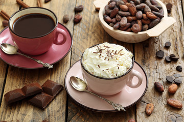 tazza di cioccolata con panna e cacao grezzo su tavolo di legno rustico