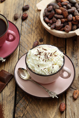 tazza di cioccolata con panna e cacao grezzo su tavolo di legno rustico