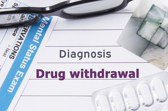 Diagnosis Drug Withdrawal. Medical notebook labeled Diagnosis Drug Withdrawal, psychiatric mental questionnaire and pills are on table in psychiatrist cabinet or counselor of this issue or problem