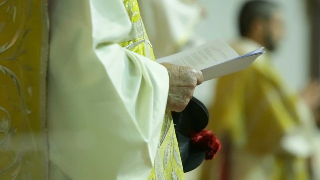 Mani di un sacerdote che stanno leggendo un libro