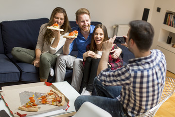 Friends eating pizza together at home