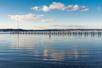 Obraz premium Zachmurzone niebo nad pomostem na jeziorze