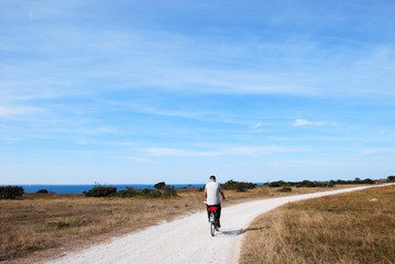 Senior biking at a winding gravel road along the coast at the swedish island Oland