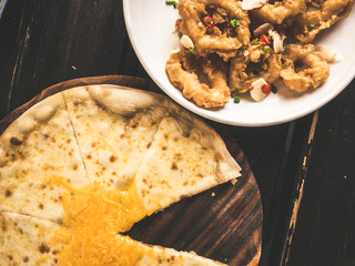 Cheese pizza on wooden plate.