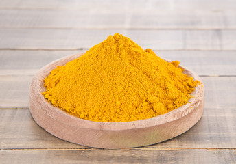 Turmeric powder on the wooden background - Curcuma longa