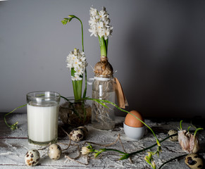 Still life with milk, bread, eggs and hyacinths in glass vases.