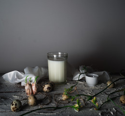 glass of milk on a wooden table. quail eggs, freesia. space for text