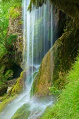 Fototapeten Vorhang eines kleinen Wasserfalls über moosbewachsenen Felsen © AVTG