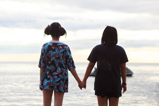 Concept of best friends with 2 girl hold hands on the beach.