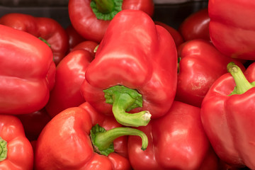 Closeup of a stack of red bell peppers on a vegetable market. Ecologic grown paprika fruits.