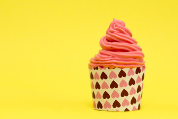 pink cupcake with delicious cream on yellow background