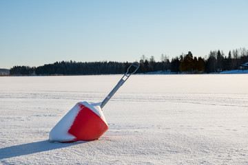 Large red buoy stuck in the ice on a clear freezing day in Sweden